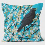 blackthorn blackbird cushion shows blackbird in blackthorn bush against turquoise background