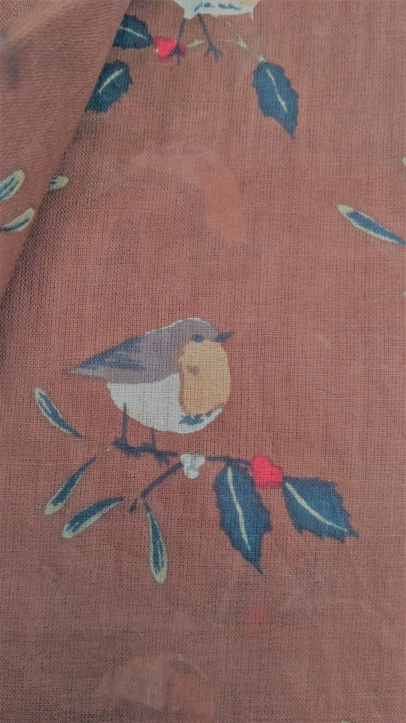 detail of robins on holly leaves against a brown fabric background