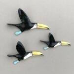 flying toucan trio of three ceramic birds facing right on a grey wall