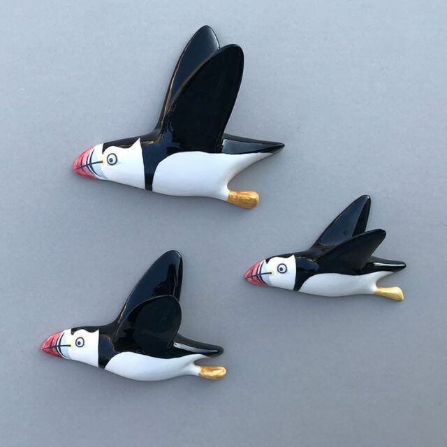 flying puffin trio three ceramic puffins facing left against a wall