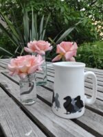 Black and white jug on beige table with pink roses behind