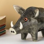 close up of wild boar money box grey with white tusks and red eyes