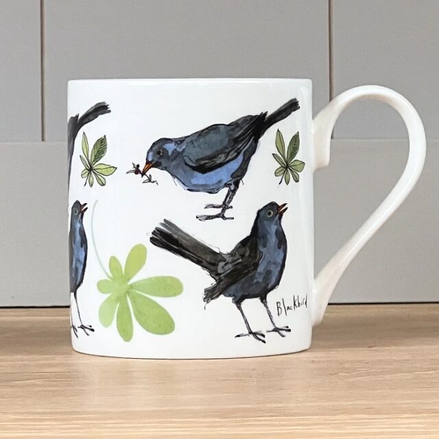 Five Blackbird mug by madeleine floyd shows the bird depicted in five different poses in black against a white background with some leaves