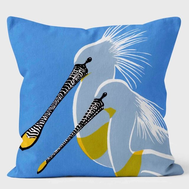 Spoonbill Pair cushion shows two adult birds with long black bills and yellow on bill and chest against a bright blue background