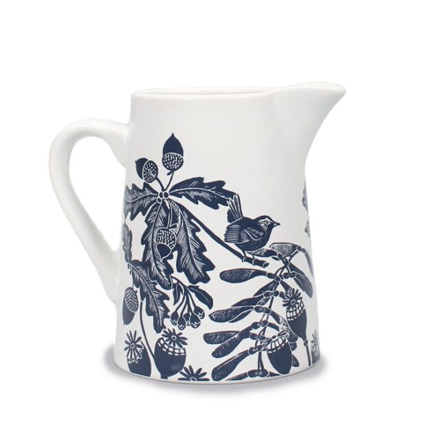 Ceramic jug navy by kate heiss shows a white jug with navy illustrations of a wren on a branch with poppy seed heads, acorns, oak leaves and sycamore seeds