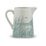 ceramic jug powder blue by kate heiss shows a white jub with pale blue illustration showing poppies and grasses growing on the beach with the sea and a seabird behind