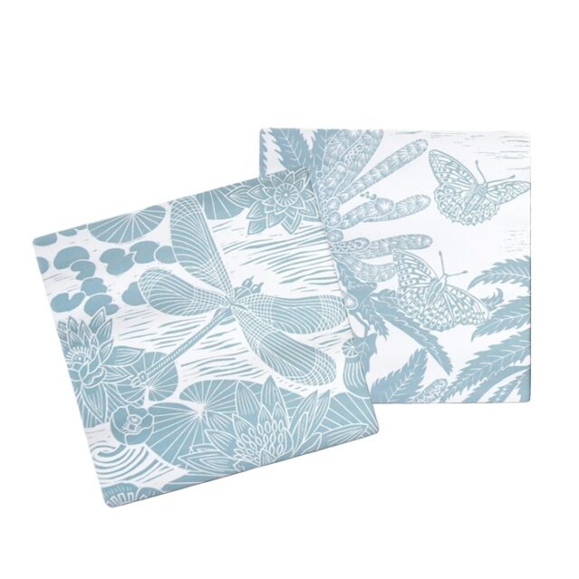 Ceramic Coasters Powder Blue by Kate Heiss shows two square blue and white ceramic coasters with illustrations of dragonflies and butterflies