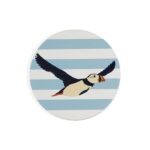 Shows a ceramic coaster with a puffin in flight against a blue and white striped background which make up the set of RSPB Ceramic Puffin Coasters