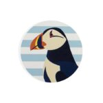 Shows the head of a puffin reproduced on a ceramic coaster with images of puffins against a blue and white background which make up the set of RSPB Ceramic Puffin Coasters