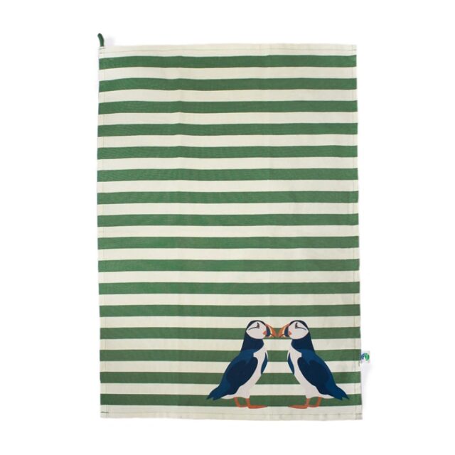 Shows the RSPB Puffin Tea Towel green with green and white horizontal stripes and two puffin birds facing each other with beaks touching in the right hand bottom corner