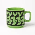 Hornsea Rabbit Mug by Magpie shoes a stylised rabbit in green against a black background, repeated around the mug