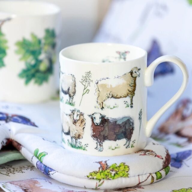 out in the fields sheep mug by madeleine floyd shows a white china mug with illustrations of sheep around it