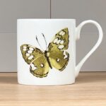 Green Butterfly Mug by Holly Lasseter shows a painting of a green and white butterfly on a white mug