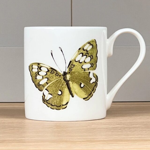 Green Butterfly Mug by Holly Lasseter shows a painting of a green and white butterfly on a white mug