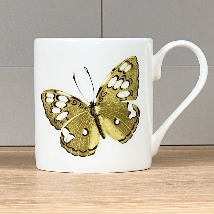 Green Butterfly Mug by Holly Lasseter shows a painting of a green and white butterfly on a white mug