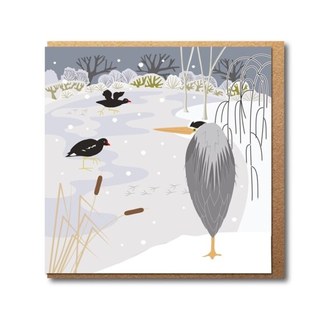 Heron and Frozen Pond Greetings Card by Rachel Hudson shows a grey heron standing on the side of a frozen pond whilst two small black birds peck on the ice